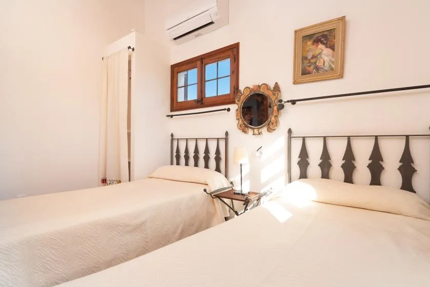 A bright bedroom with two beds and a window.