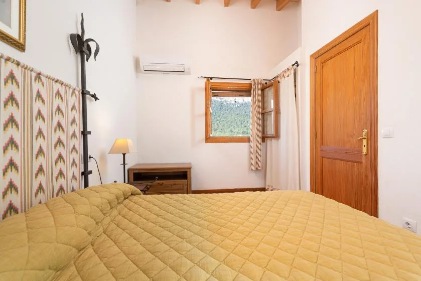 A bedroom with a bed, a small bedside table, and an open window.