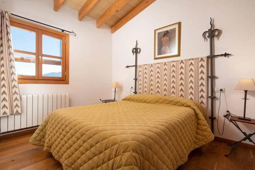 A bedroom with a quilted bed beneath exposed wooden ceiling beams.