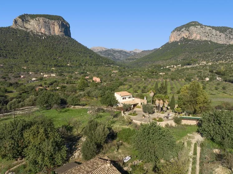 A rural valley with scattered homes and wooded hills beneath rocky cliffs.