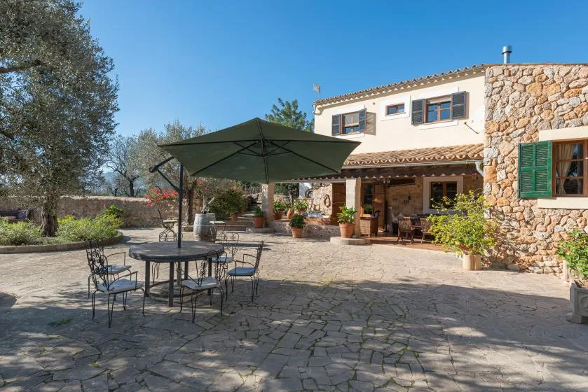 A stone-paved outdoor patio with shaded seating beside a house.