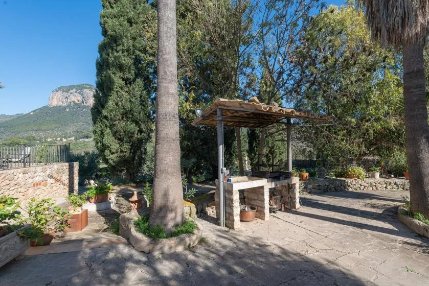 A stone-paved garden patio with a wooden pergola and potted plants.