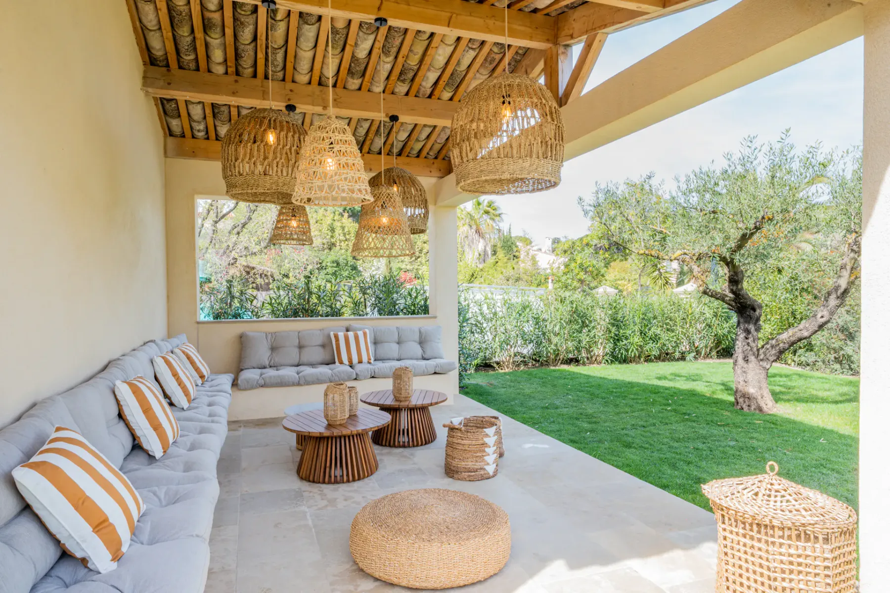 Una zona de estar exterior cubierta da a un jardín verde con un árbol.