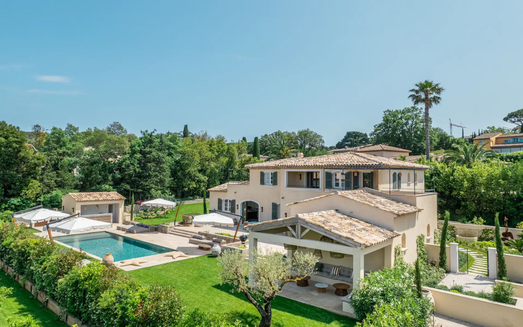 Vista de la parte trasera de una villa con un gran jardín y piscina.