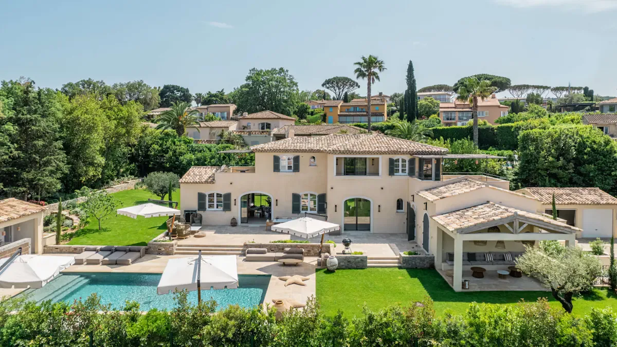 Una casa grande da a una piscina y un jardín cuidado.