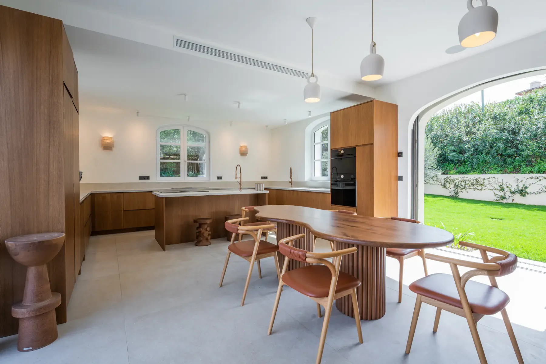 Un comedor con mesa y sillas de madera se abre a un jardín verde.