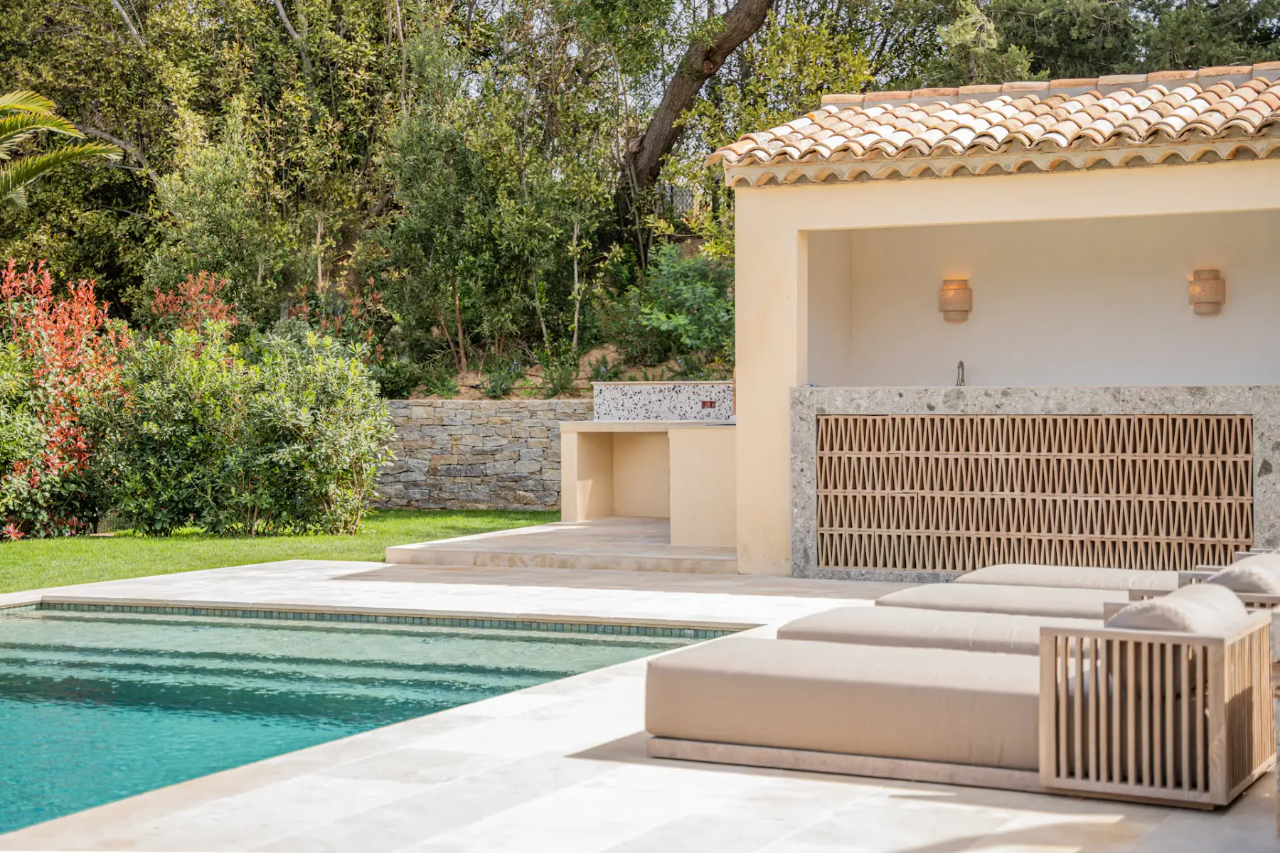 Piscina, tumbonas y una caseta de piscina en una zona ajardinada bien cuidada.