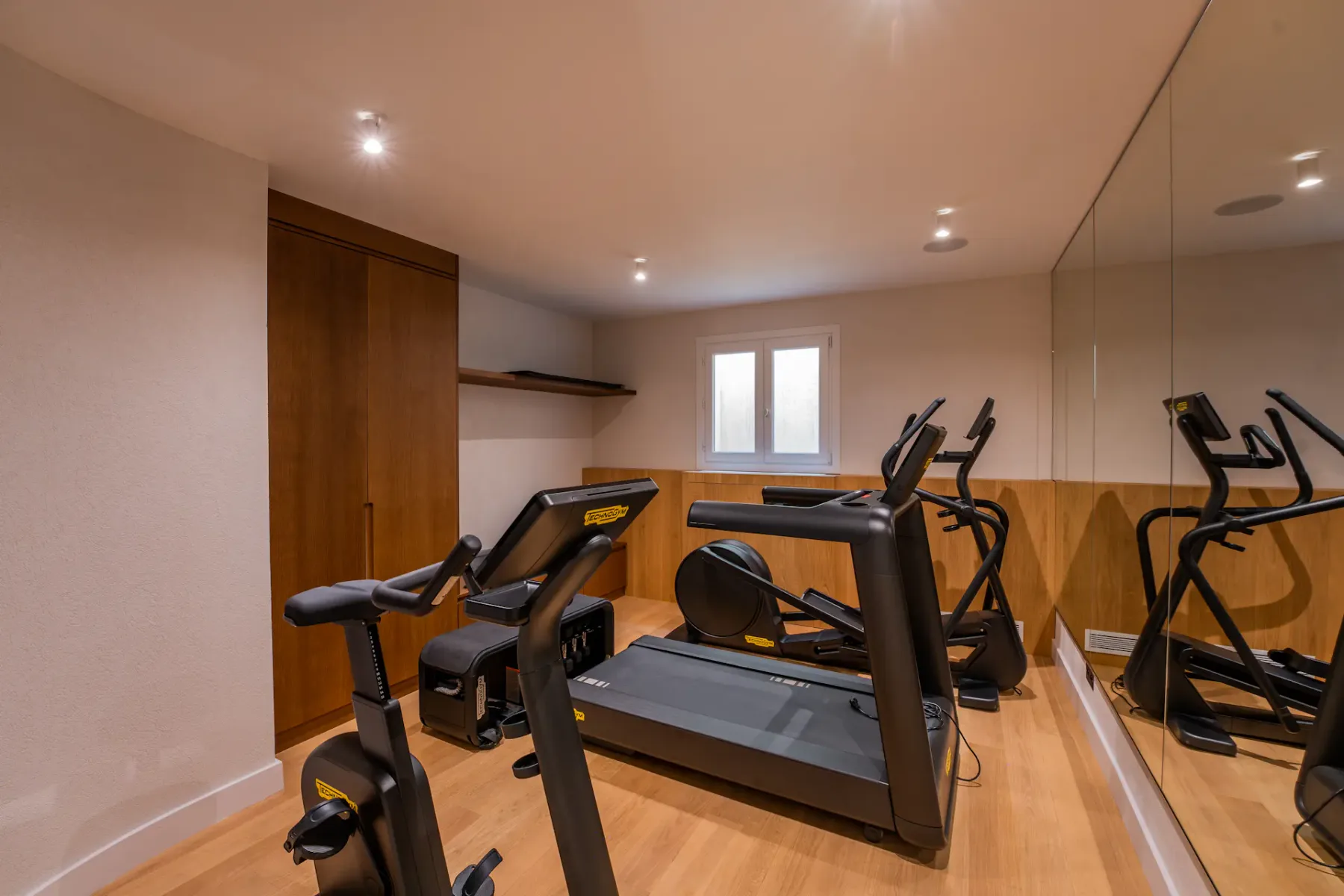 Gimnasio interior con equipo de ejercicio y una pared de espejos.