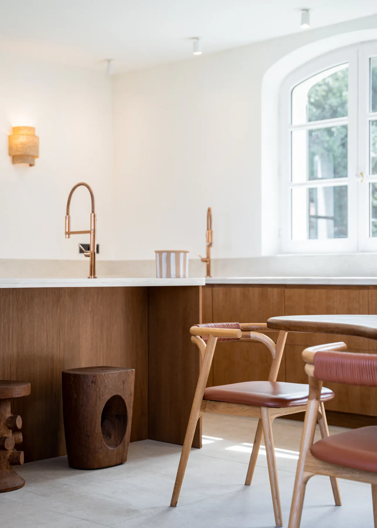 Imagen de cerca de una mesa y una silla del comedor, con la encimera de la cocina, el fregadero y una ventana al fondo.