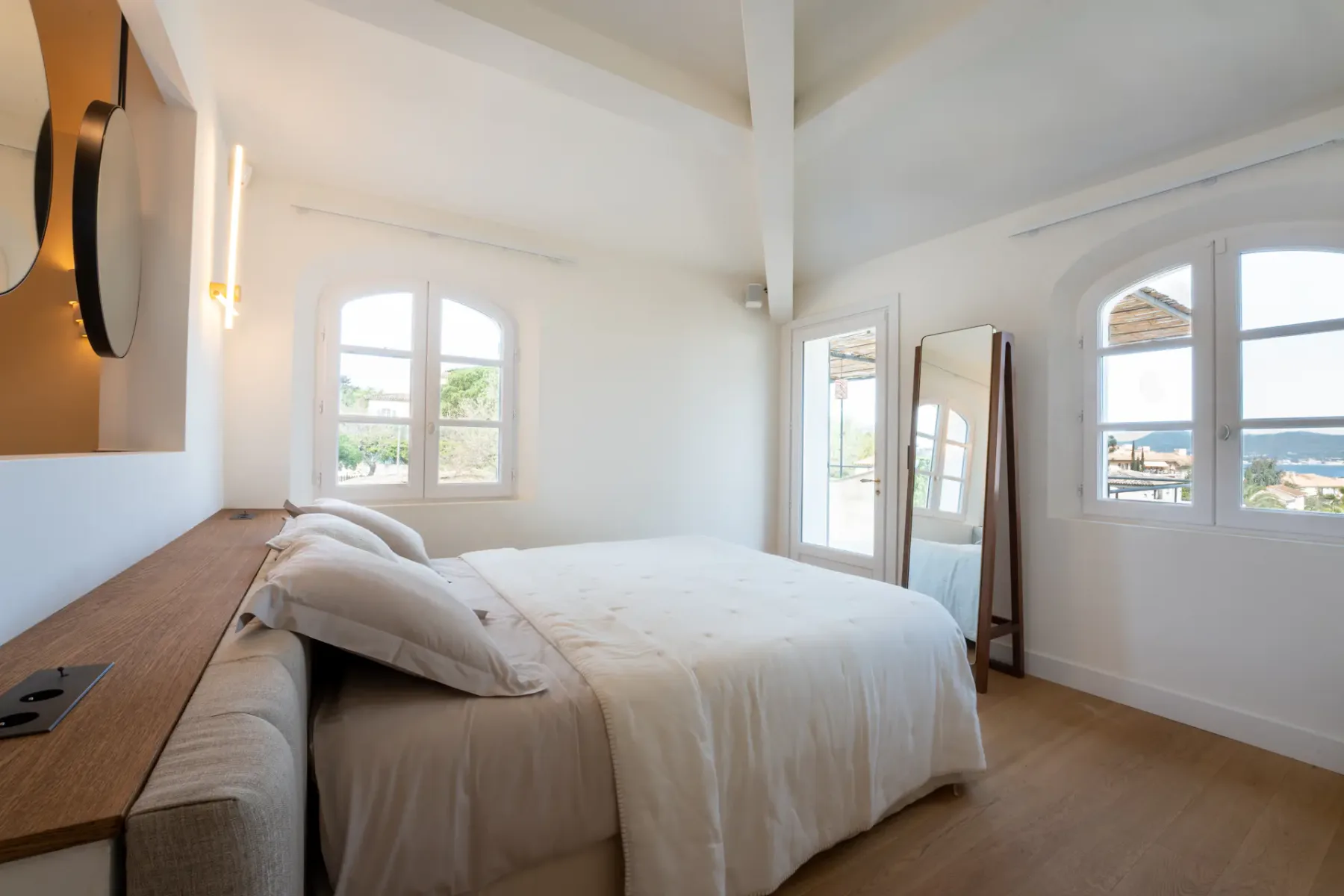 Un dormitorio luminoso con una cama y ventanas con vistas al agua.