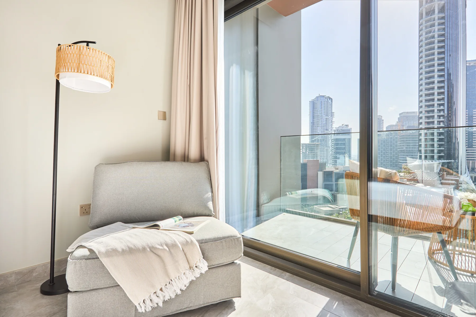 Una luminosa zona de estar con un asiento acolchado junto a puertas de vidrio que dan a un balcón.