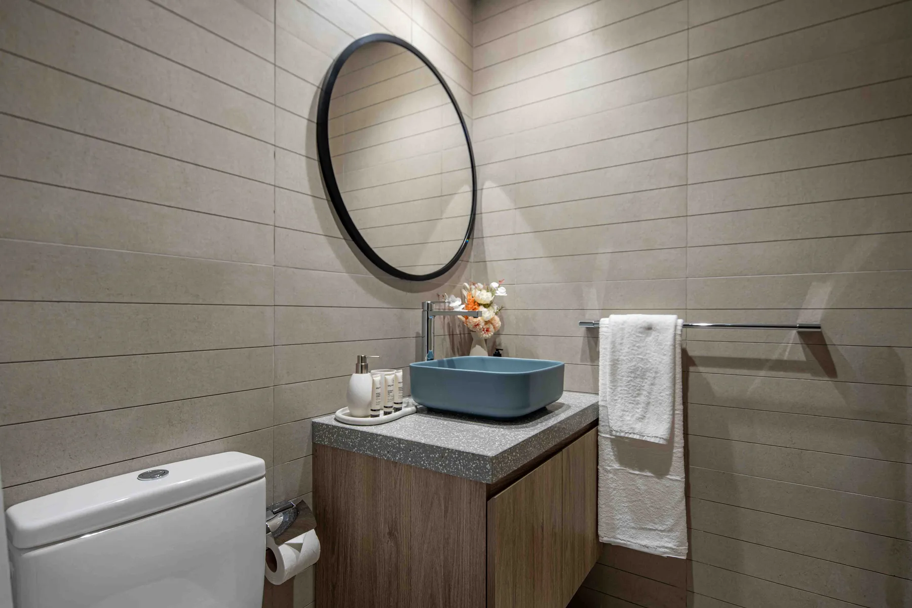 Un lavabo de baño con una pila azul sobrepuesta, un espejo ovalado y un inodoro.