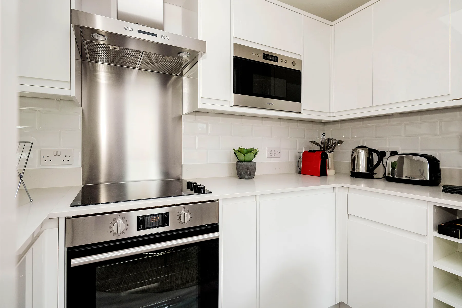 Una cocina blanca luminosa con electrodomésticos de acero inoxidable y un salpicadero de azulejos.