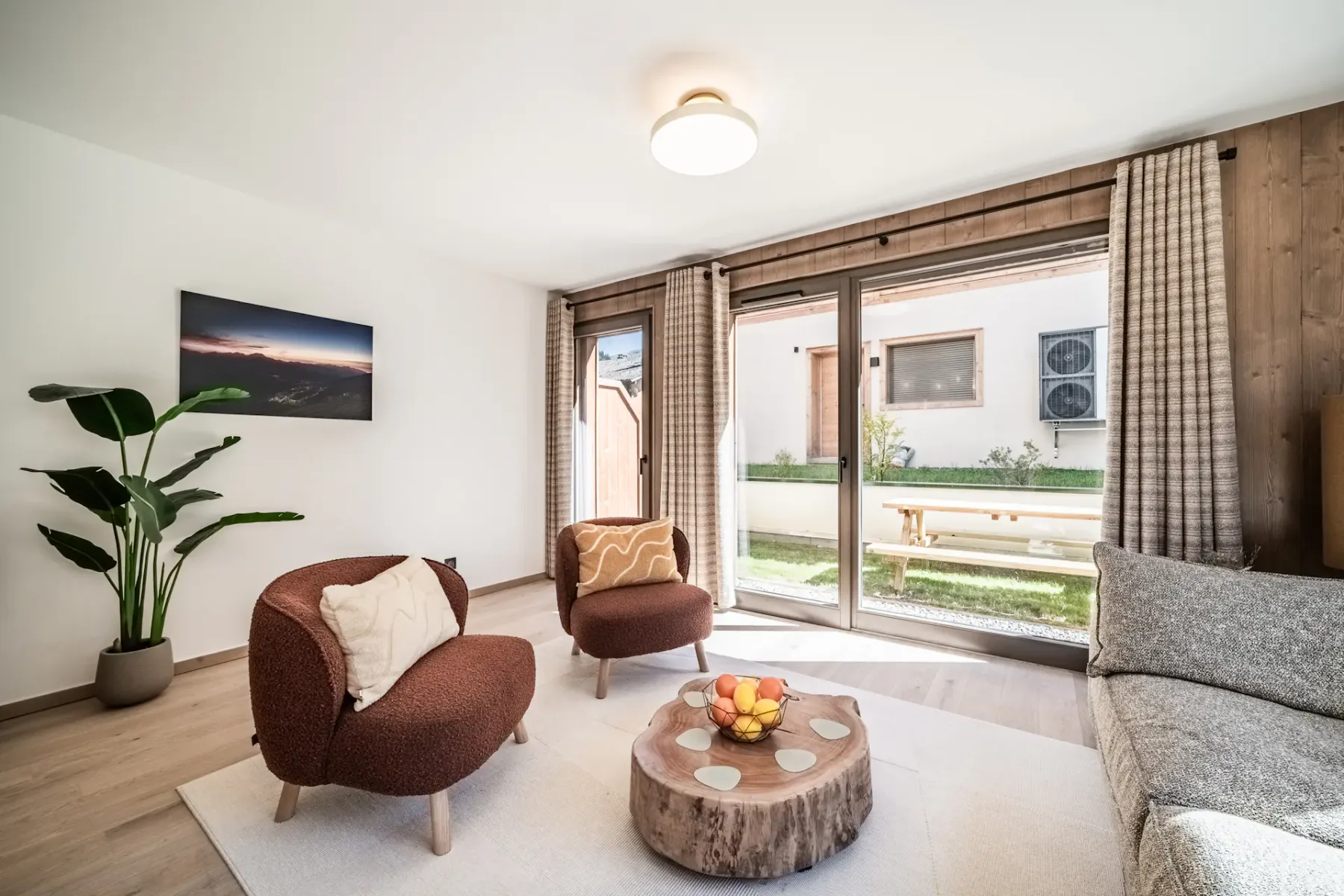 Sala de estar con asientos curvos, una mesa de centro baja de madera y puertas corredizas de vidrio.