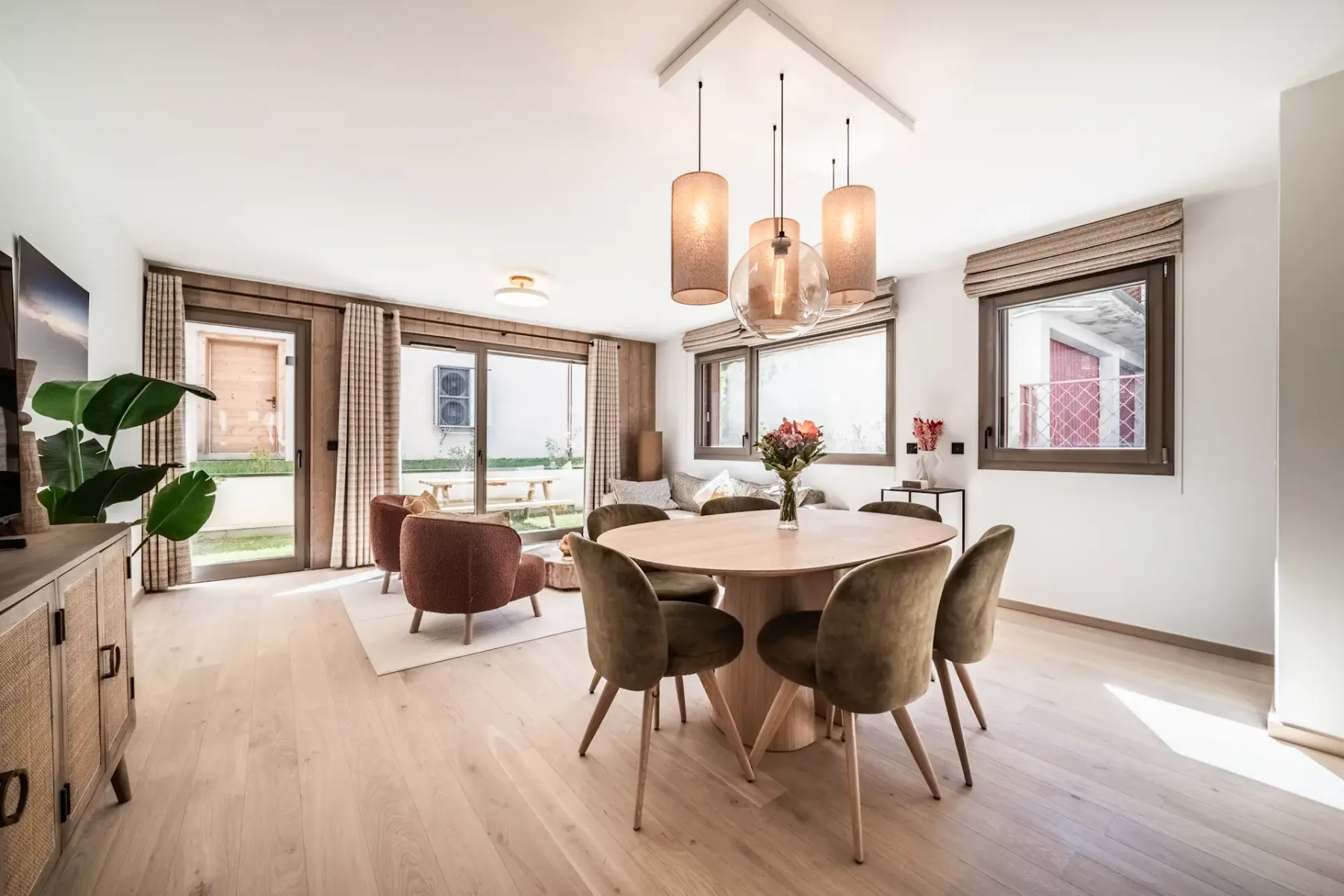 A bright dining and living area with a round table and large windows.