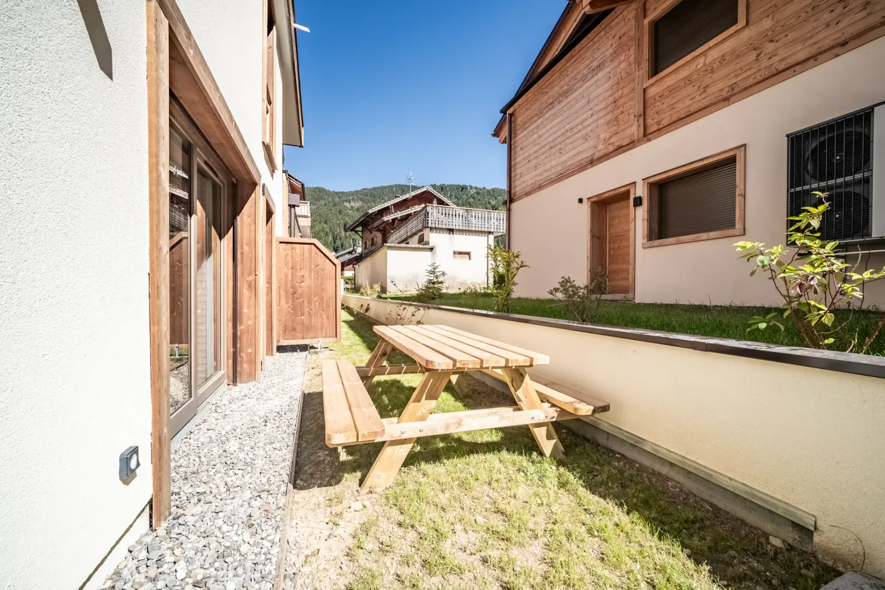 A picnic table sits in a small grassy courtyard between buildings.