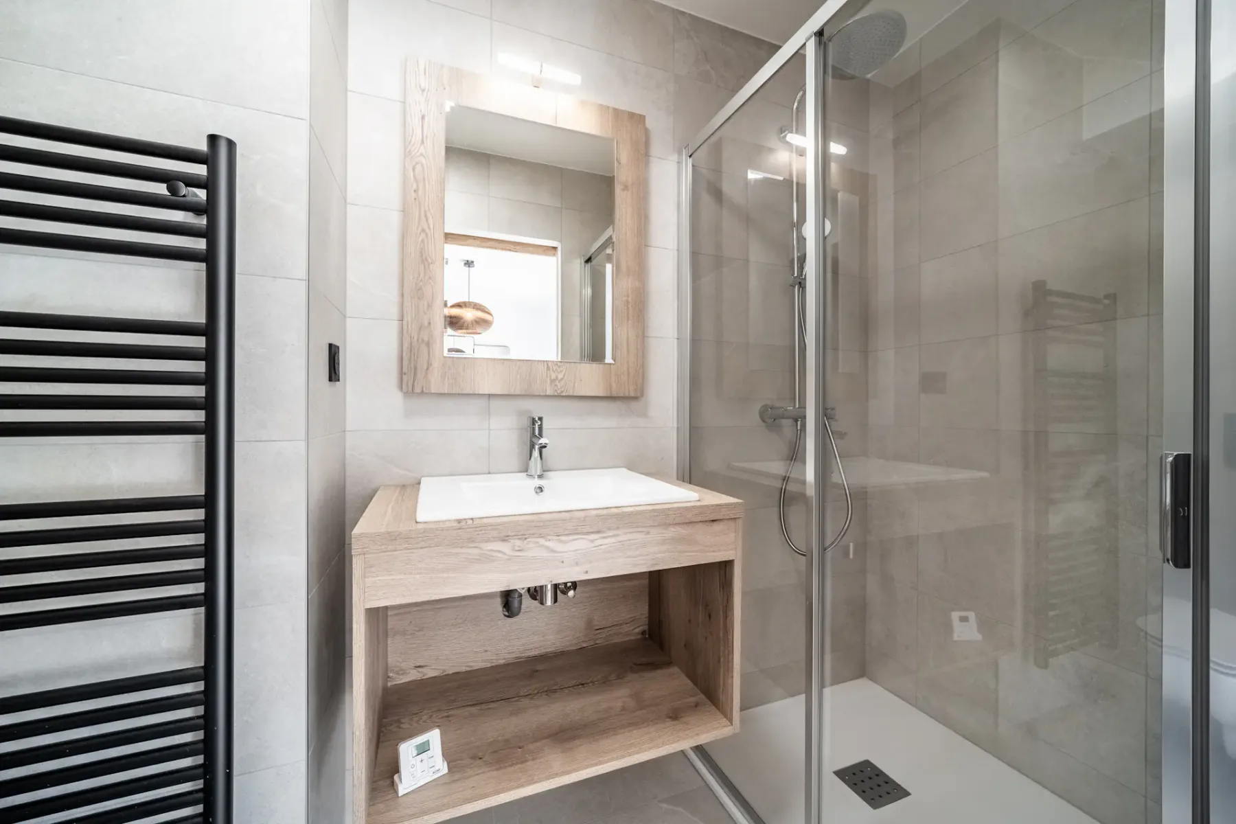 A tiled bathroom with a wall-mounted sink and glass shower.