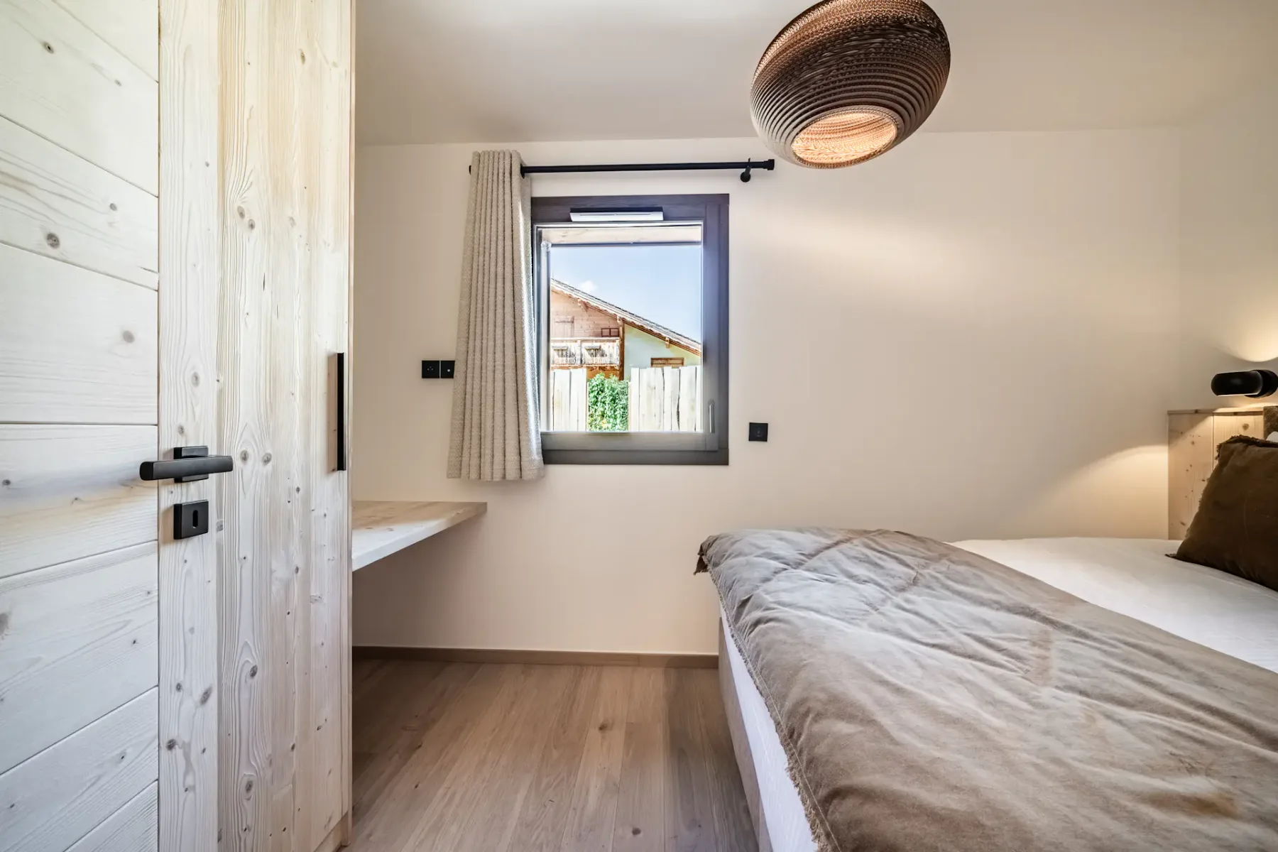 Bedroom with a bed, a window, and a woven pendant light.