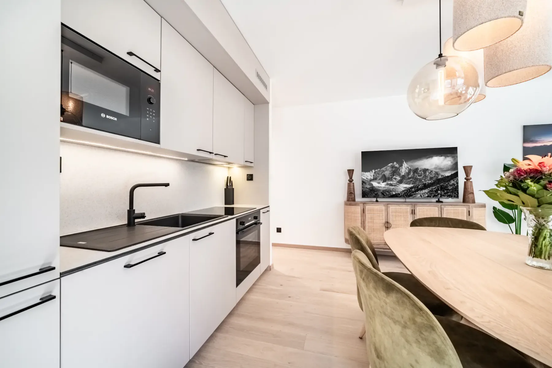 An open-plan kitchen and dining area with white cabinets and an oval table.