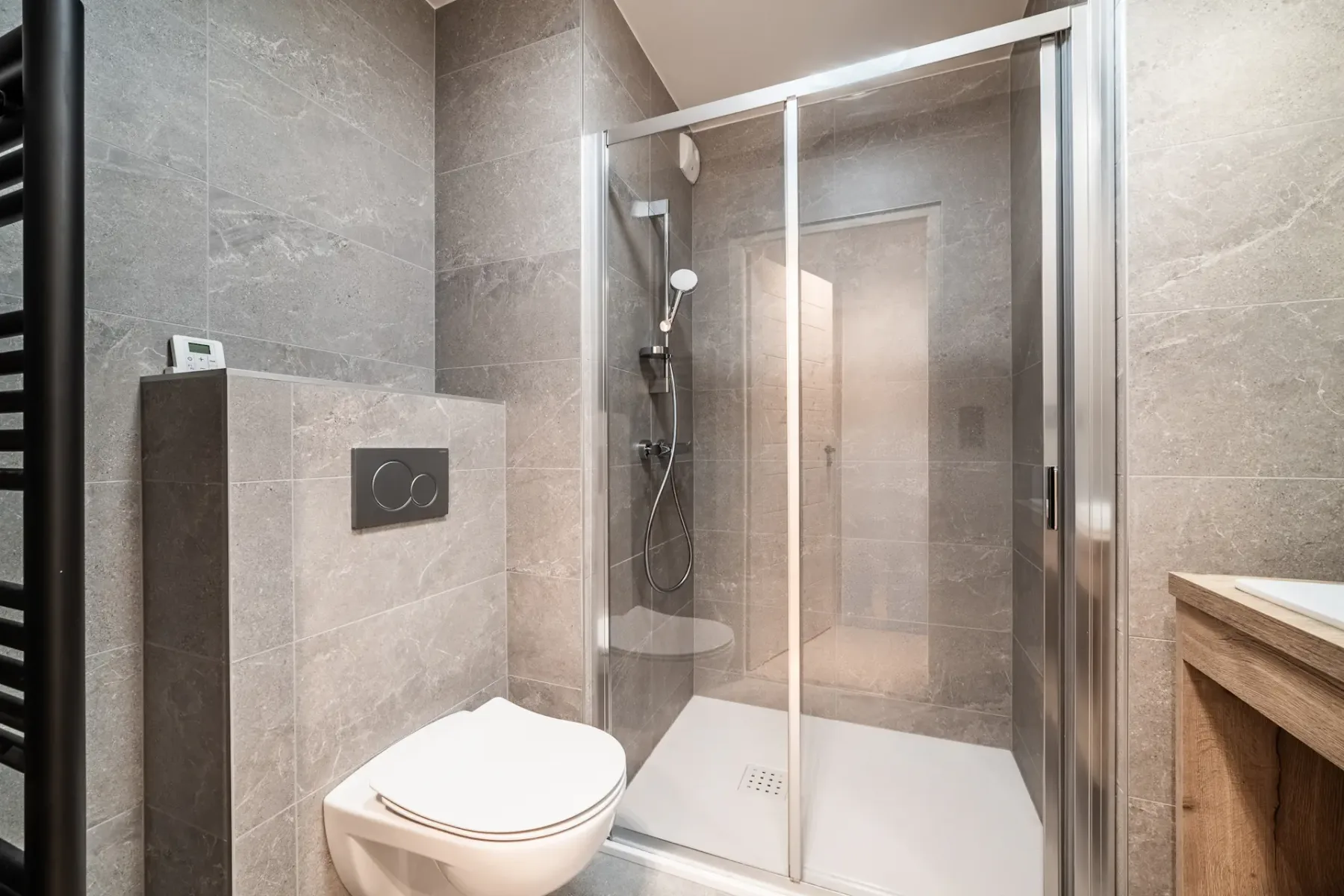 A tiled bathroom with a glass shower and a wall-mounted toilet.