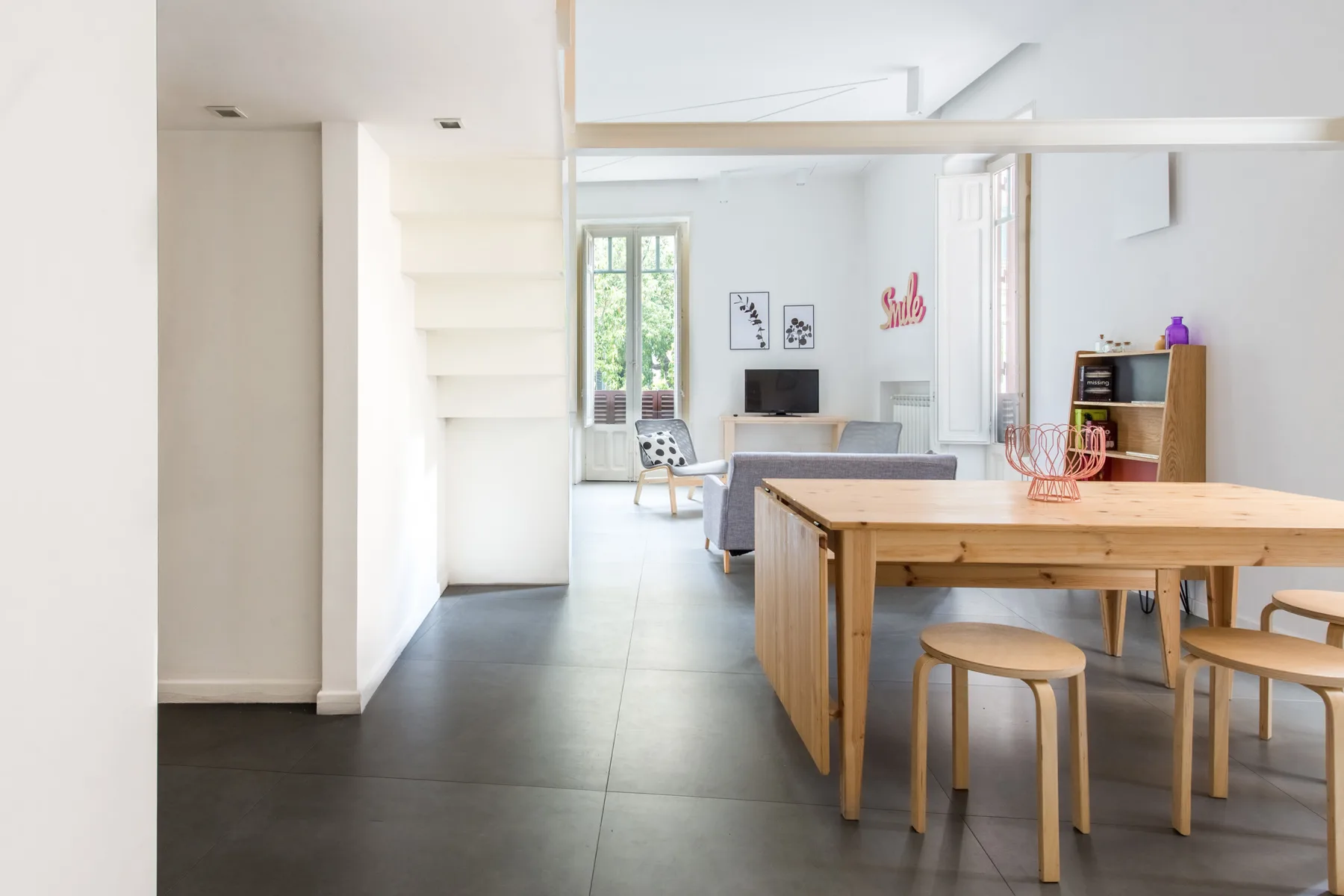 A bright open-plan dining and living area with a wooden table and seating.