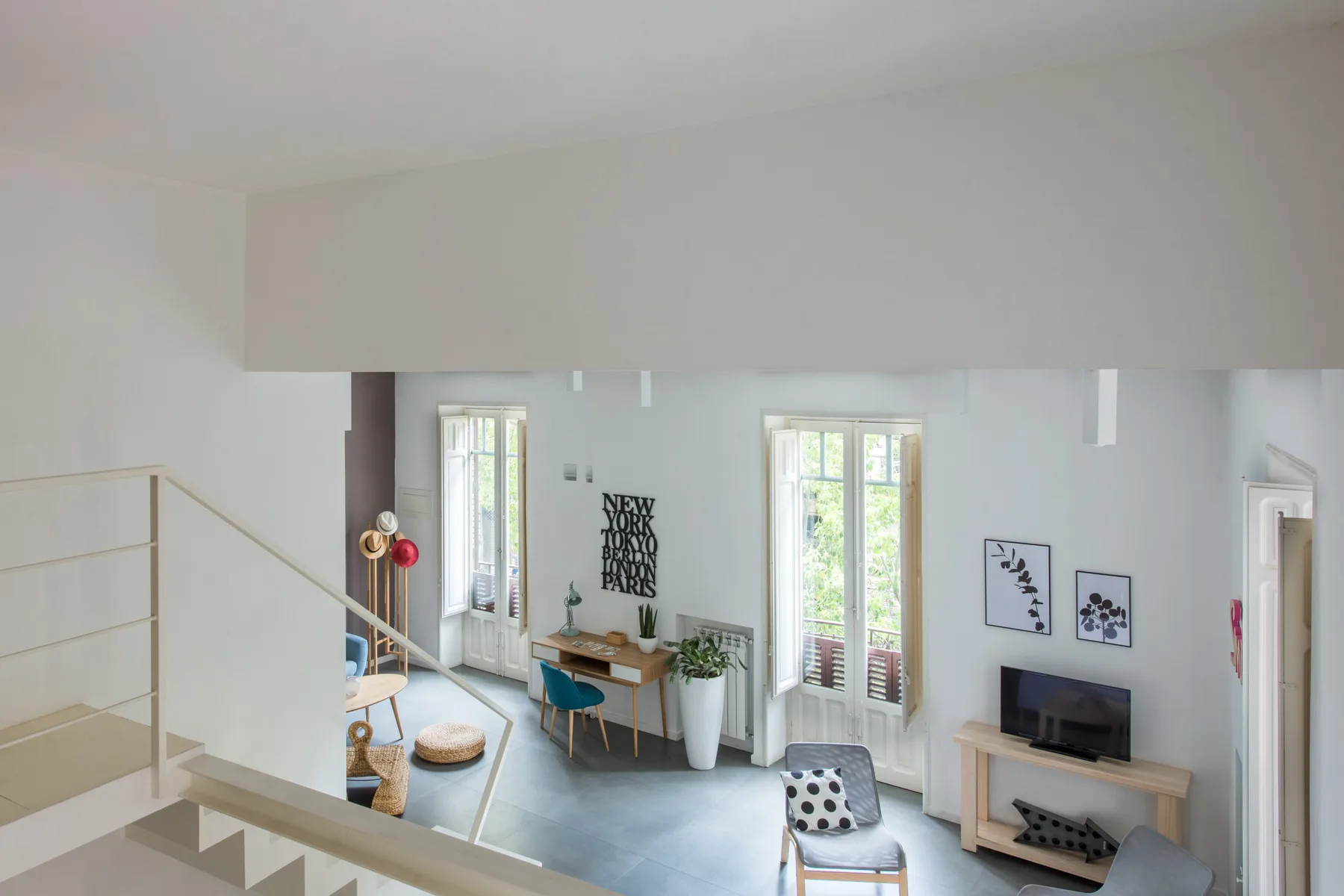 A bright living room with a television, seating, and tall windows.