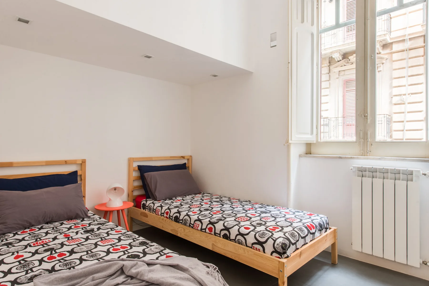 A bright bedroom with two beds and a large window.