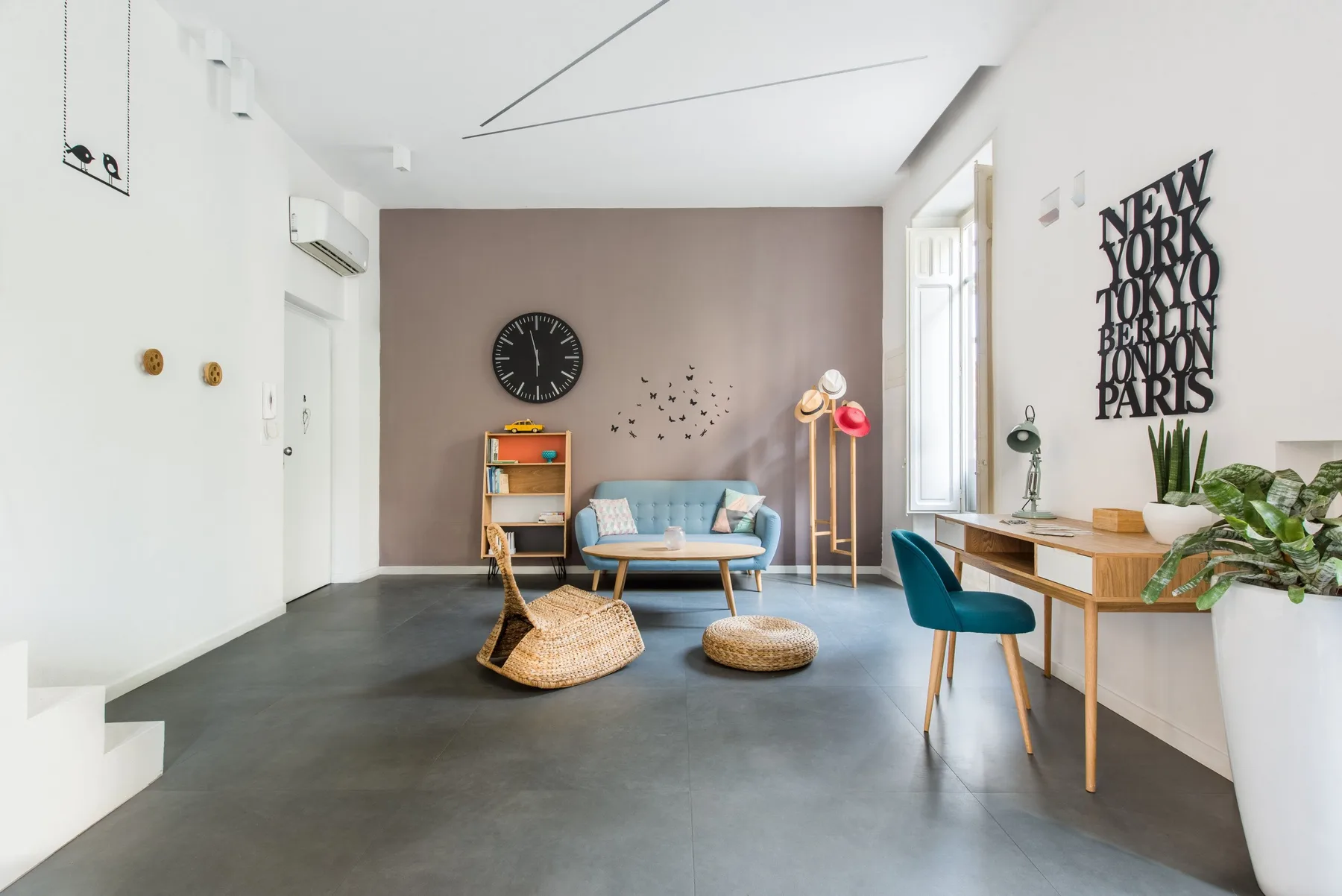 A bright living room with a seating area, desk, and tall windows.