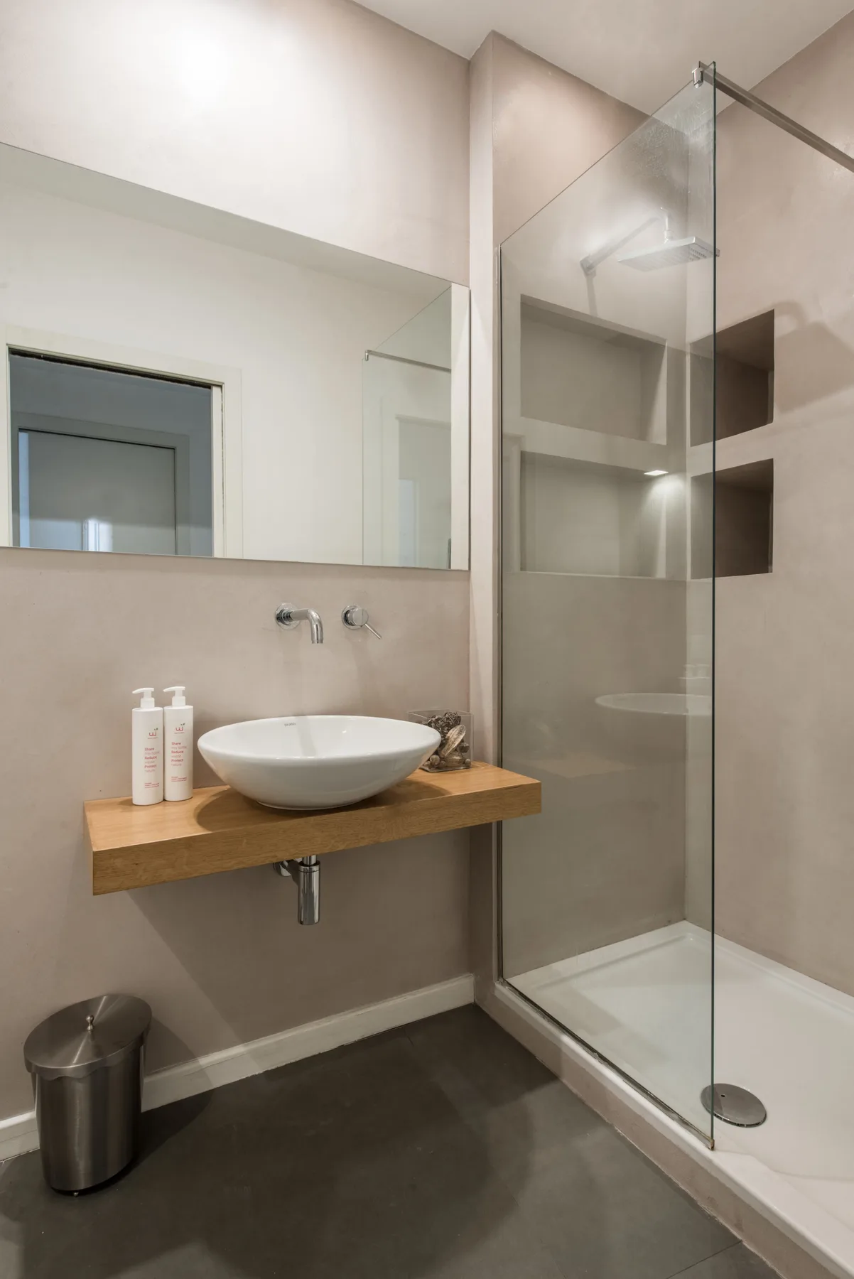 A modern bathroom with a wall-mounted sink and glass shower.
