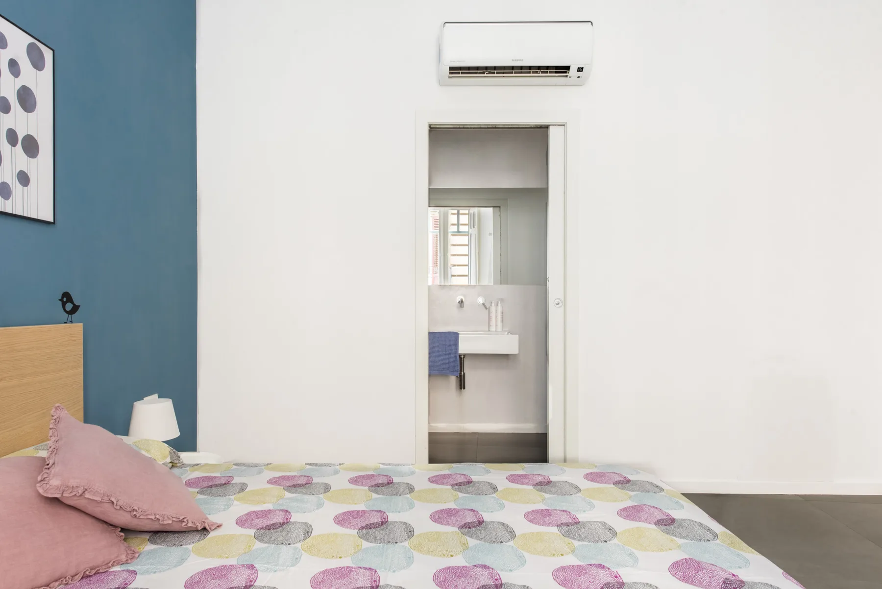A bedroom with patterned bedding and an open doorway to a bathroom.
