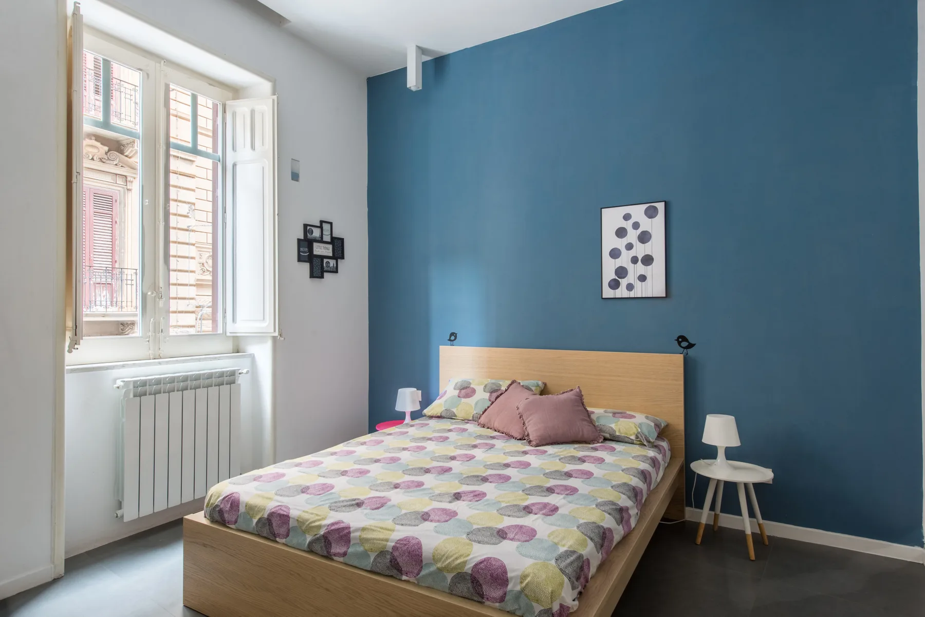 A bedroom with a wooden bed, patterned bedding, and a blue accent wall.