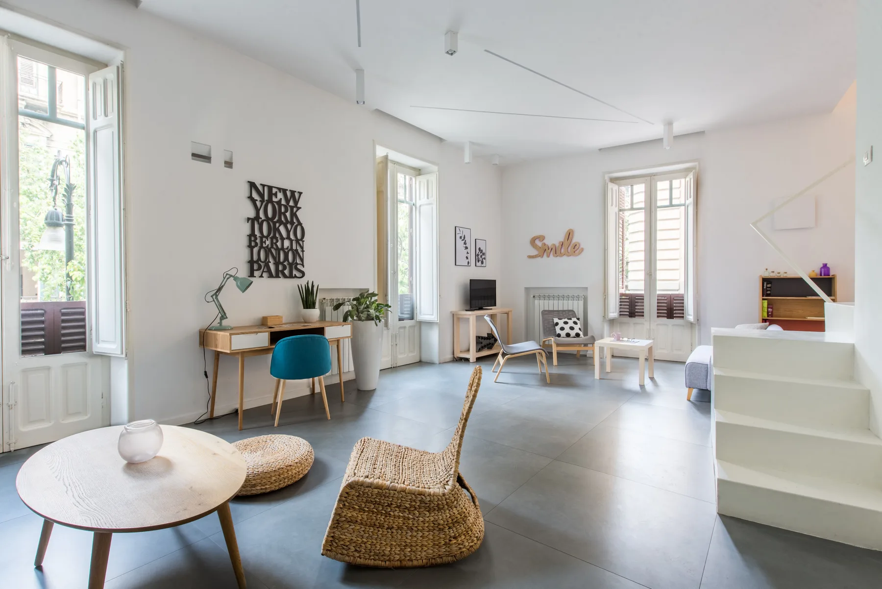 Bright living room with seating, a desk, and tall windows.
