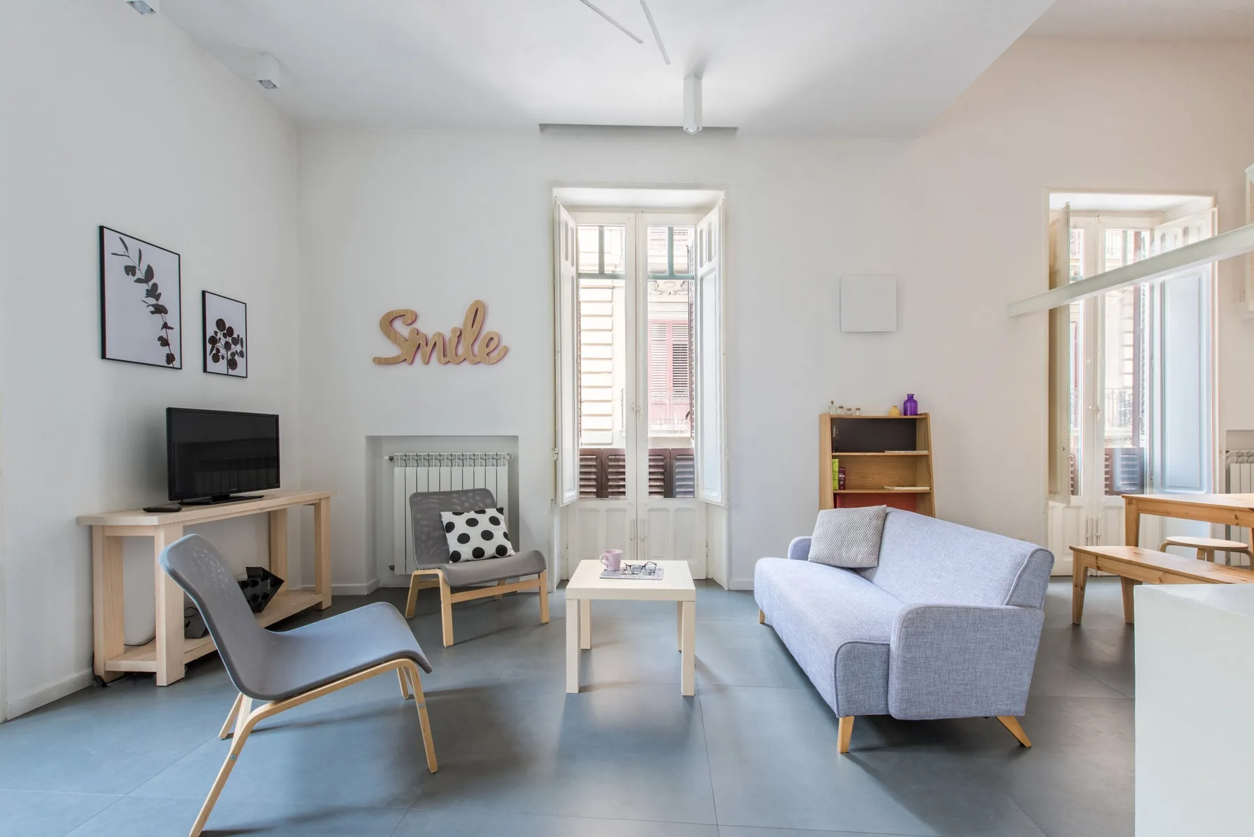 A bright living room with seating, a coffee table, and tall windows.