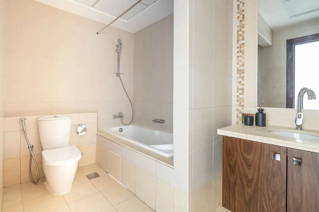 Un baño luminoso con bañera, ducha, inodoro y lavabo.