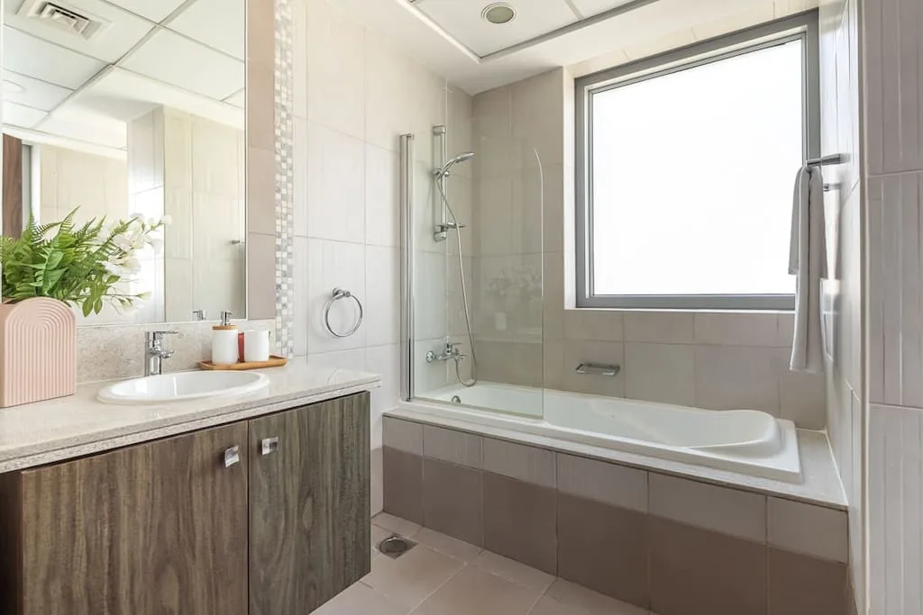Un baño luminoso con bañera, ducha y lavabo.