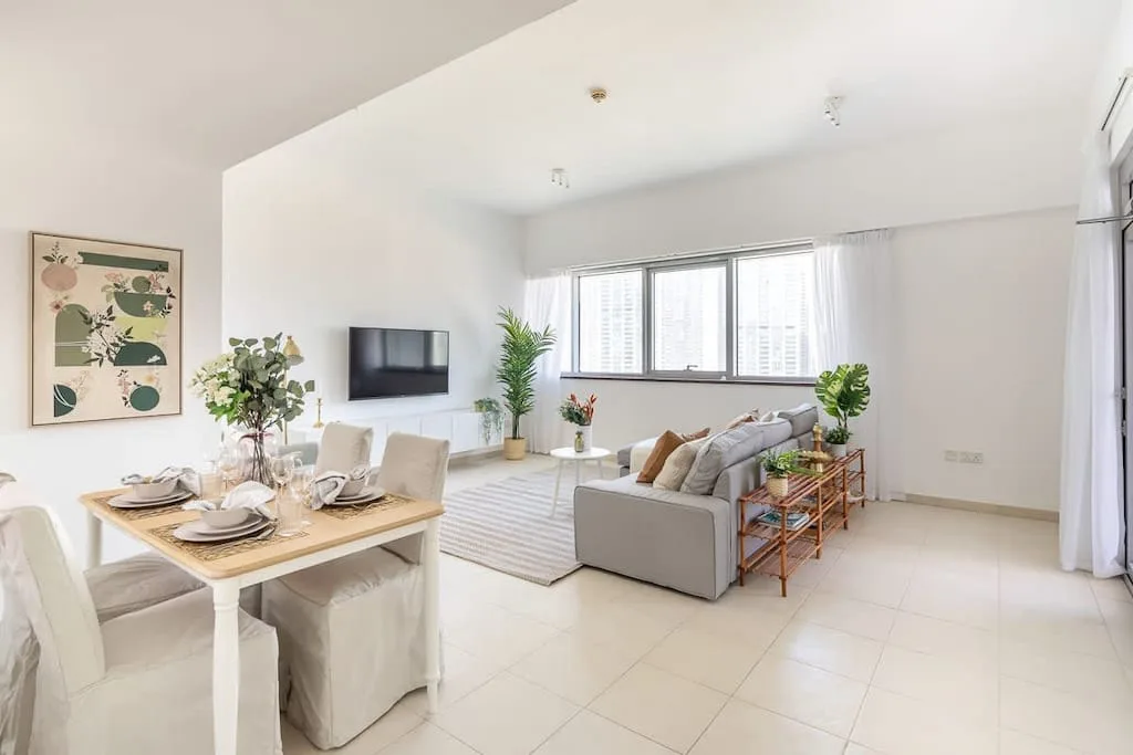 Una luminosa sala de estar y comedor de concepto abierto, con grandes ventanas y asientos.