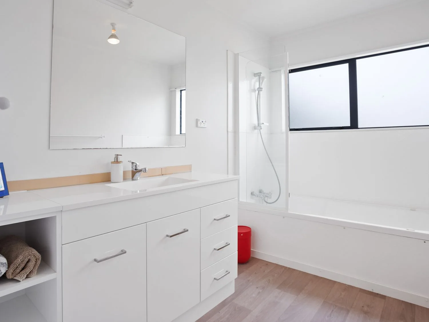 Un baño con un lavabo blanco, un espejo grande y una bañera con ducha.