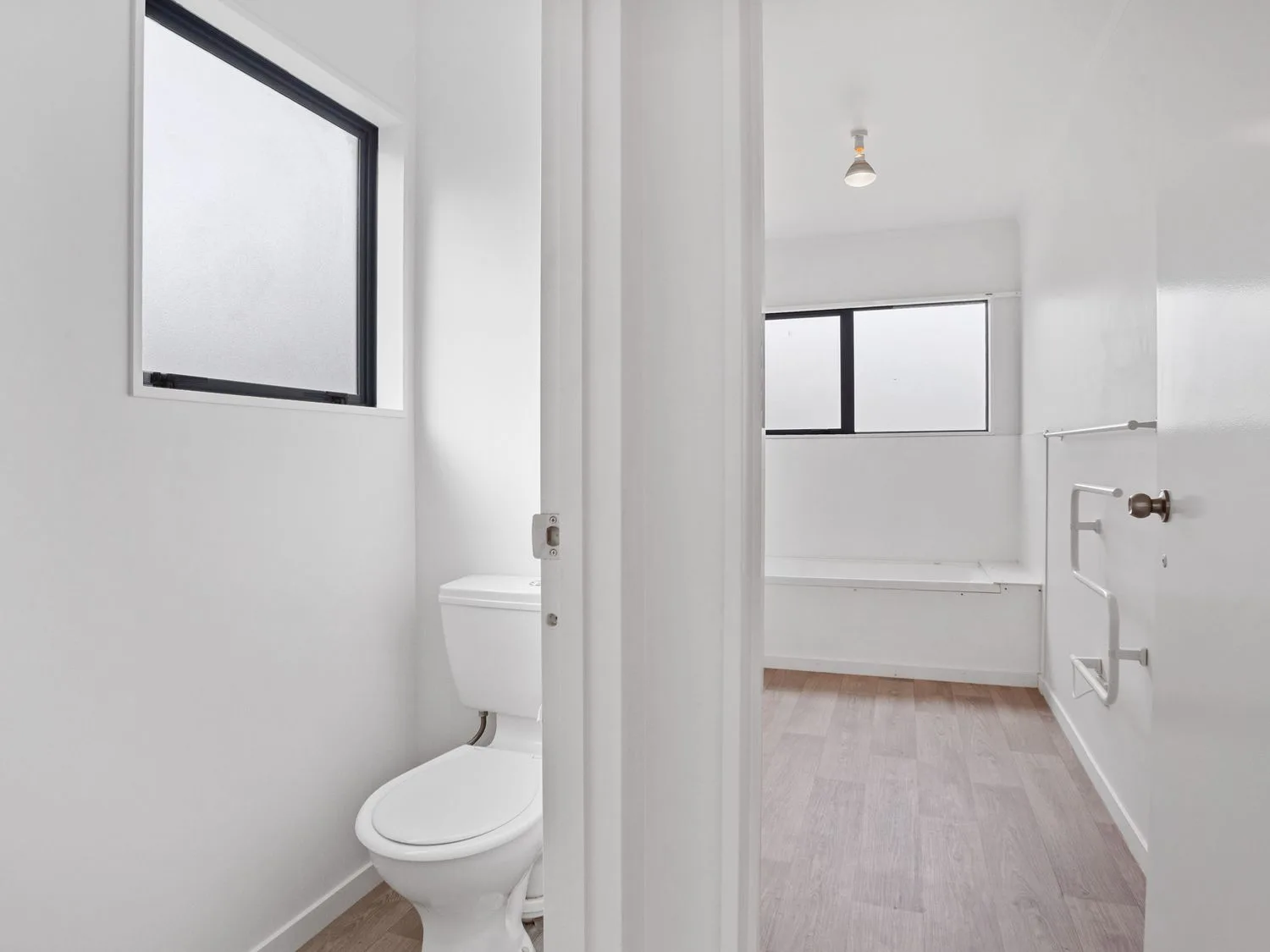 Un baño con inodoro, bañera y ventanas.