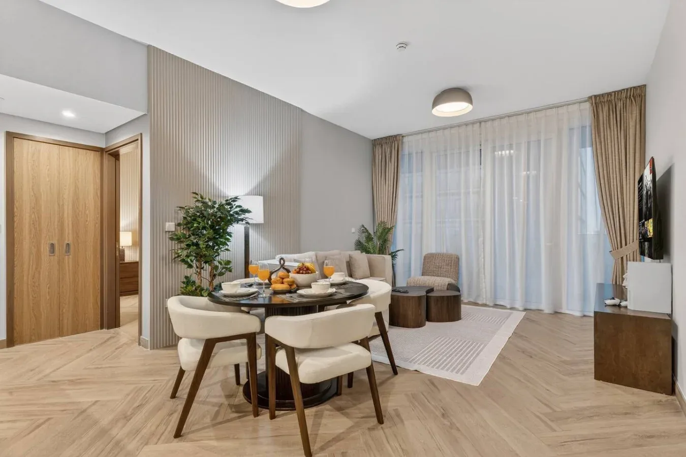A living and dining area with a table, seating, and large curtained windows.