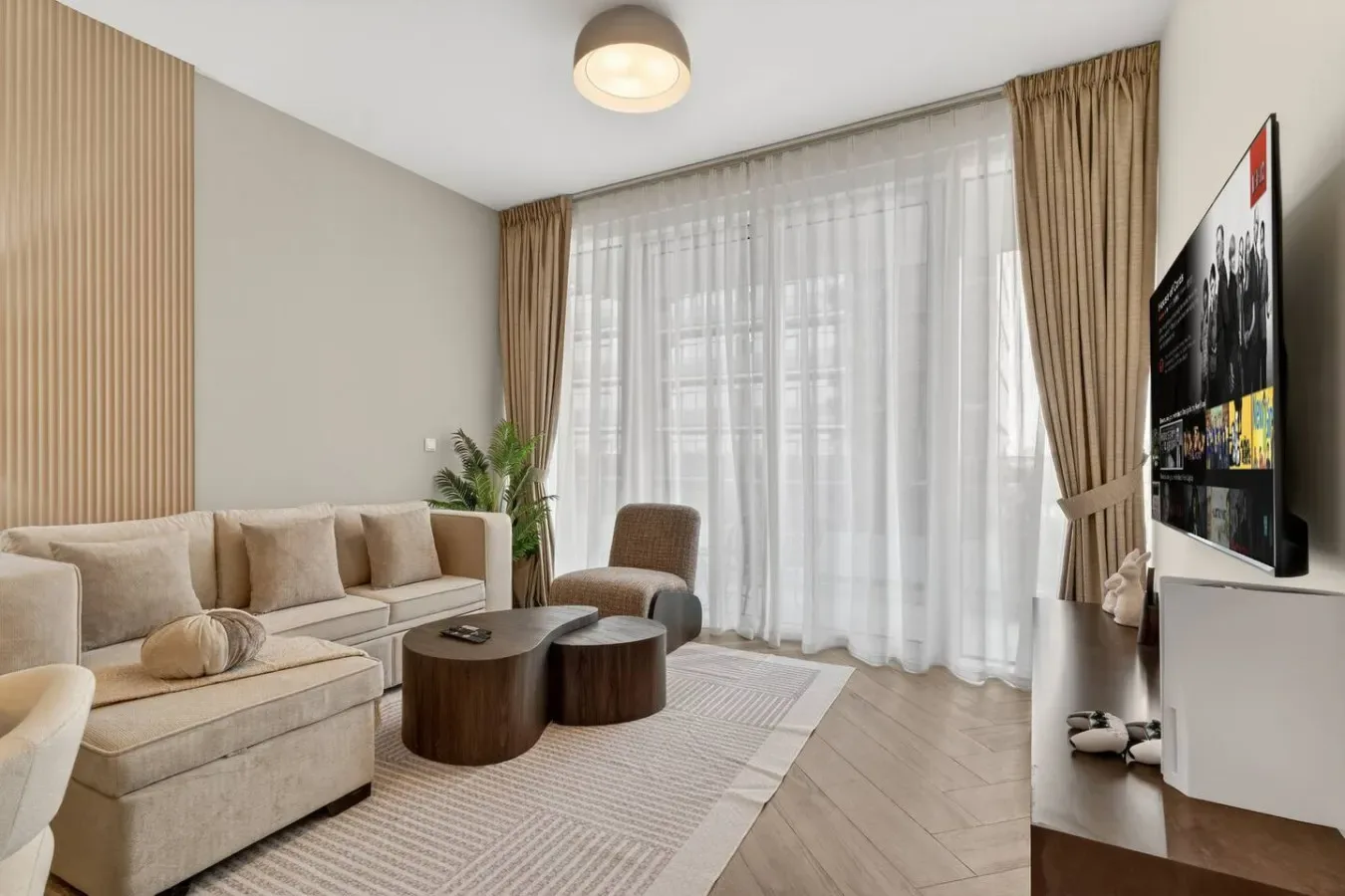 A living room with seating, a coffee table, and a large curtained window.
