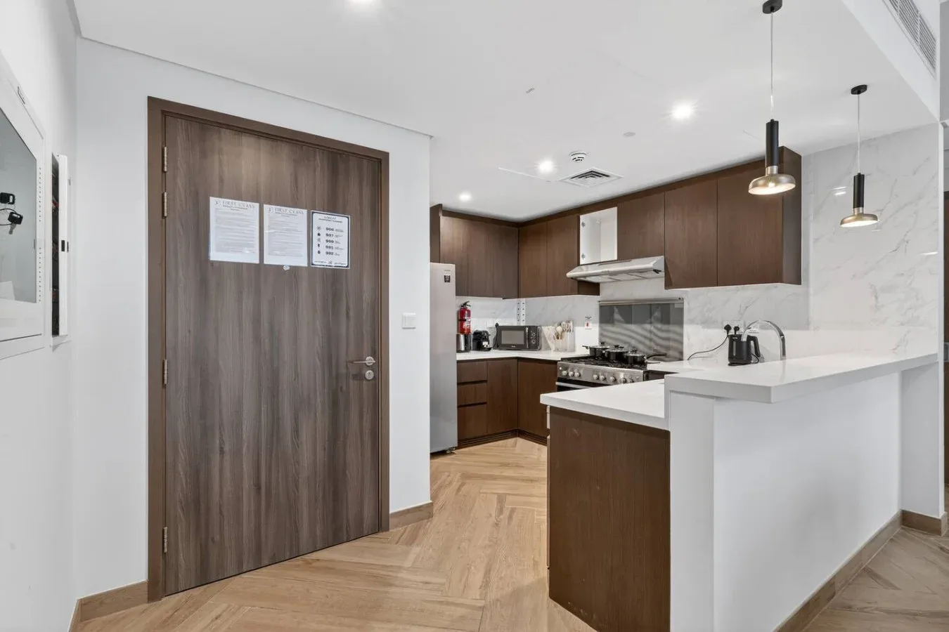 A modern kitchen with dark wood cabinets, white counters, and a central island.