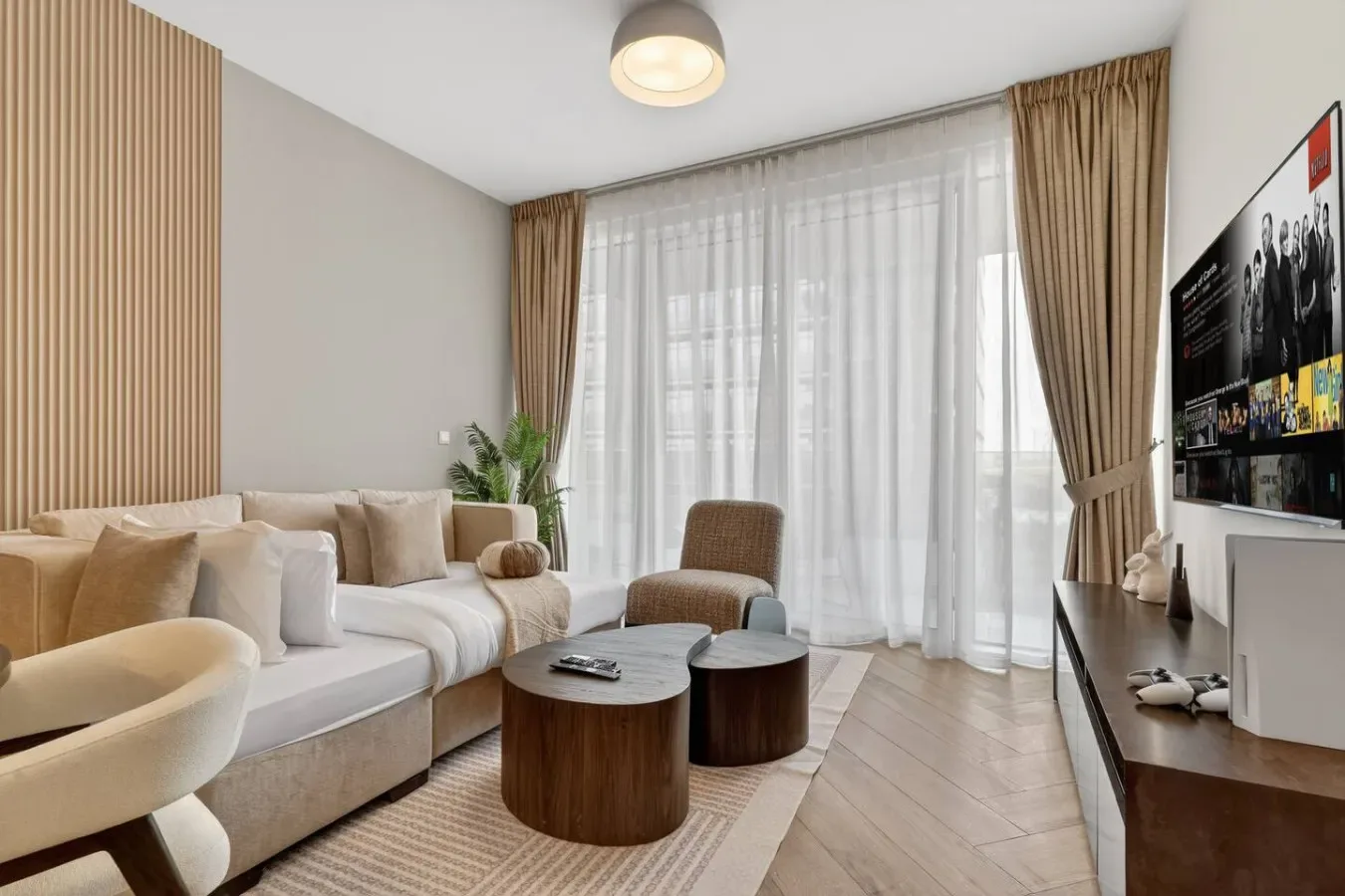 A living room with seating, round tables, and a large curtained window.