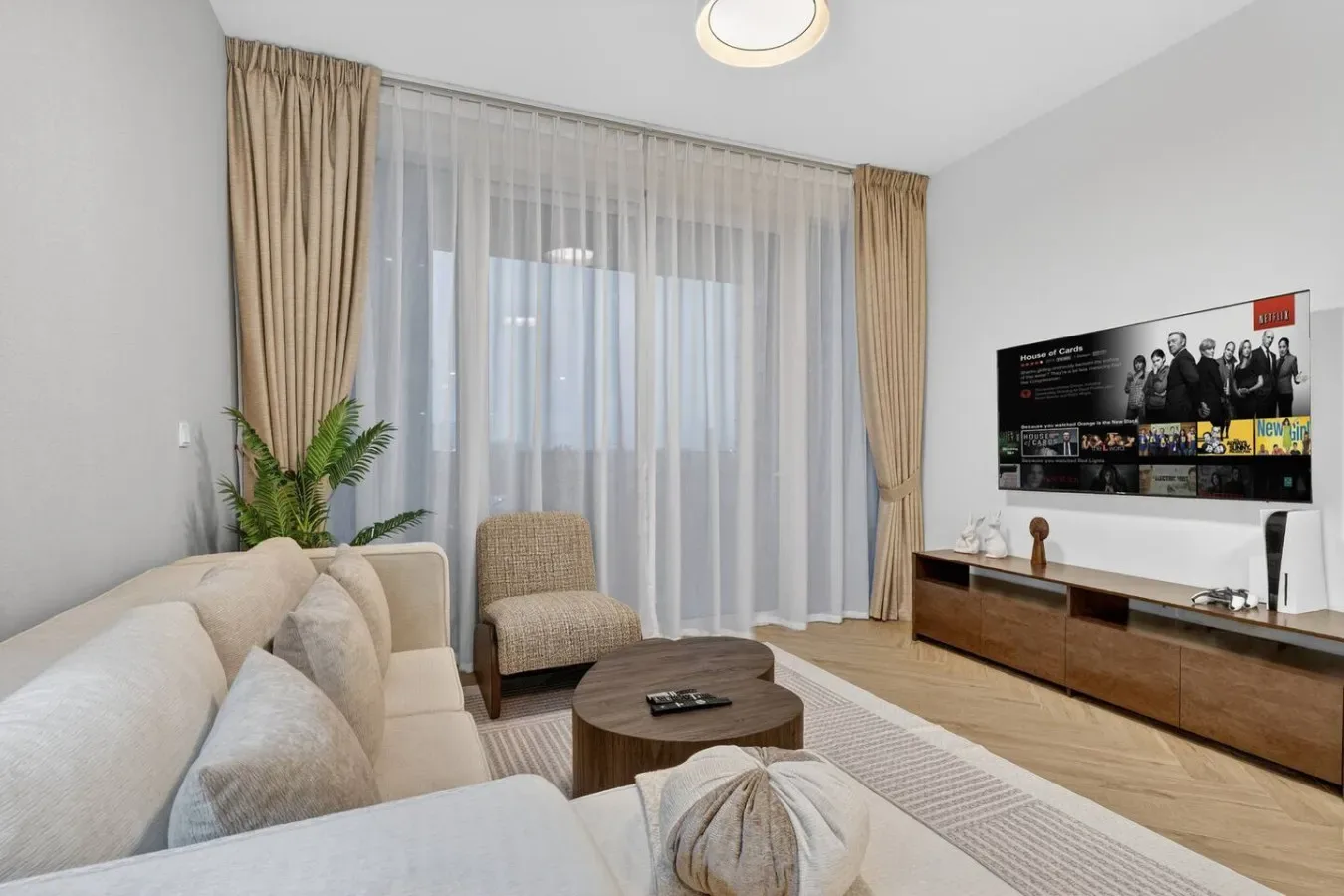 A living room with seating, a coffee table, and large curtained windows.