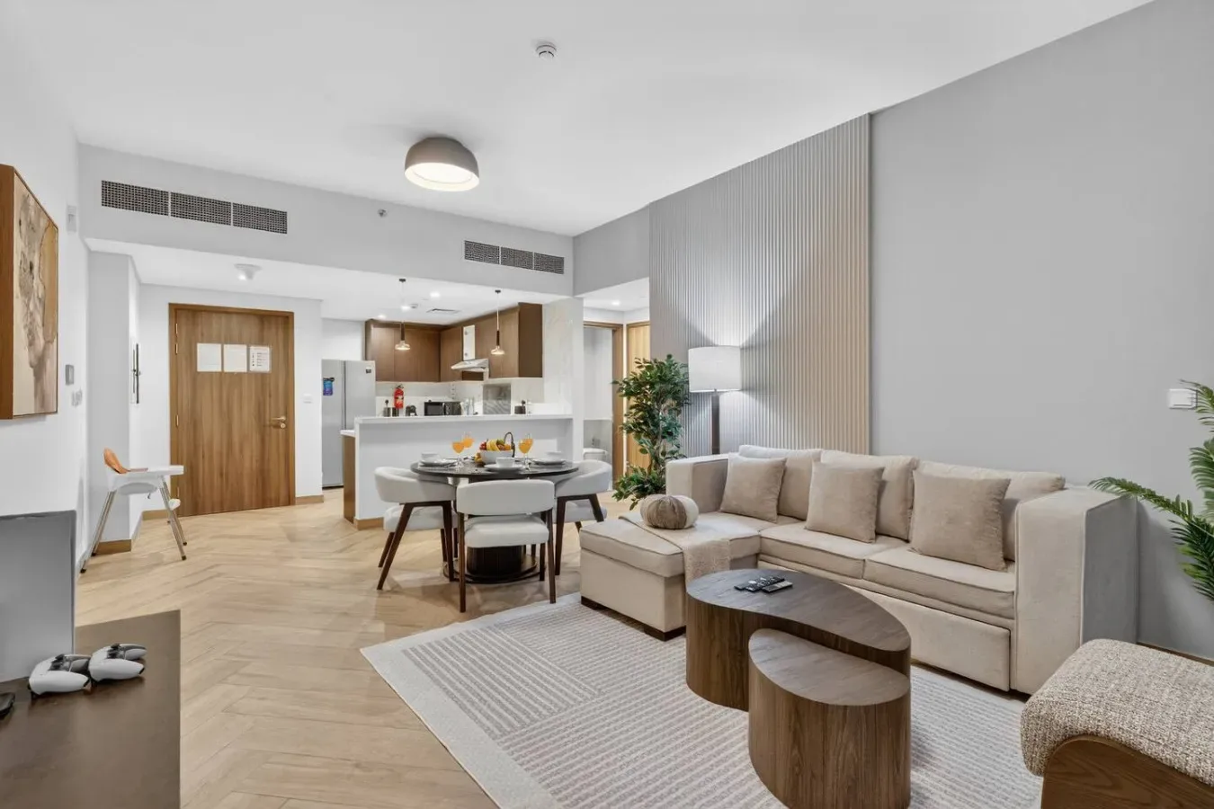 A bright living and dining area with a sectional sofa beside an open kitchen.