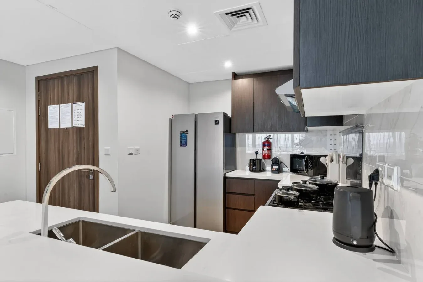 A modern kitchen with a large island and stainless-steel refrigerator.