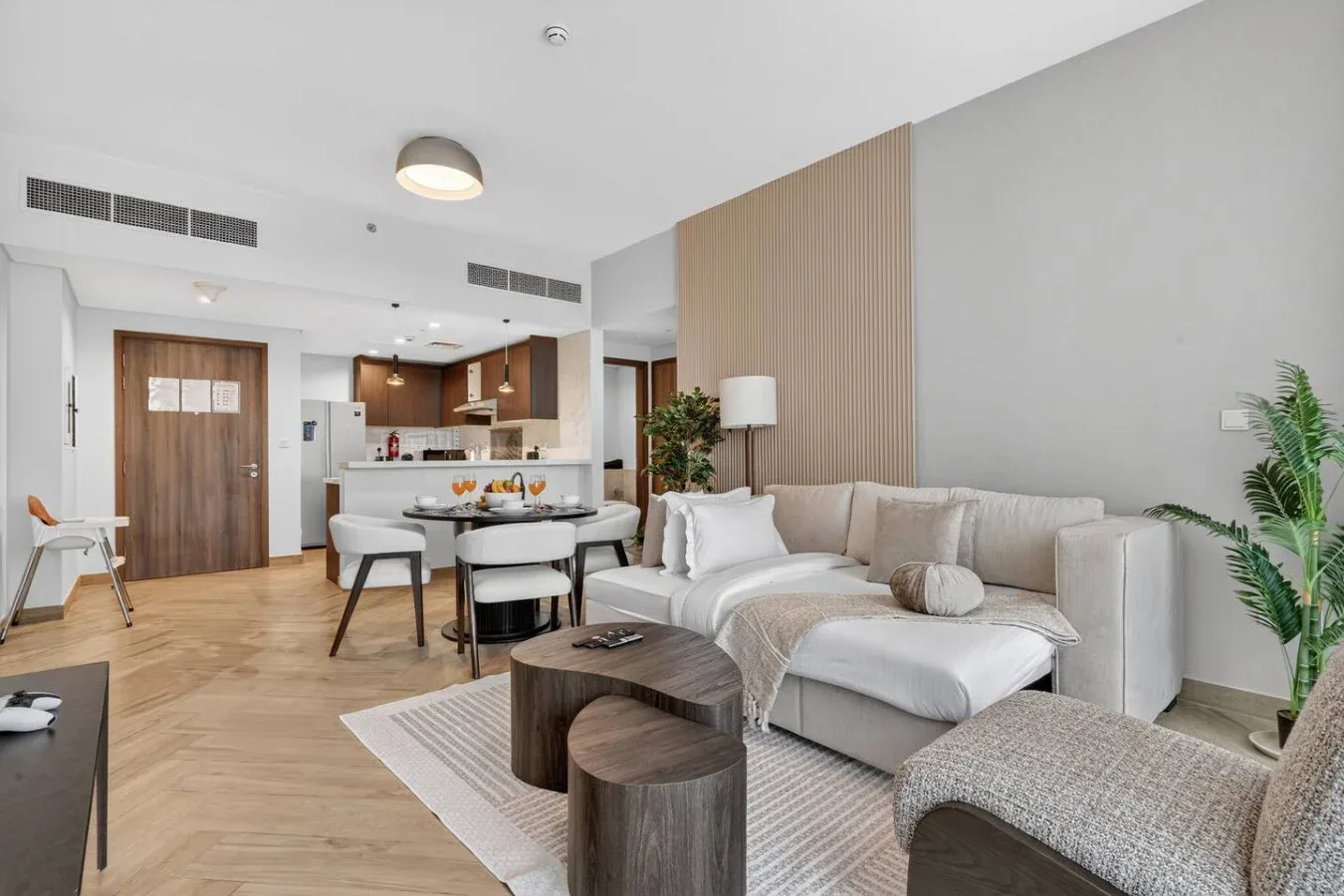 A bright living room with seating, a dining table, and an open kitchen.