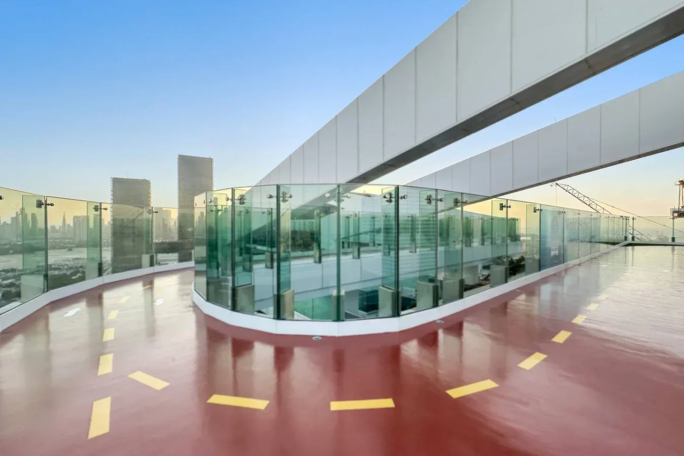 A rooftop terrace with glass railings and a glossy red floor.