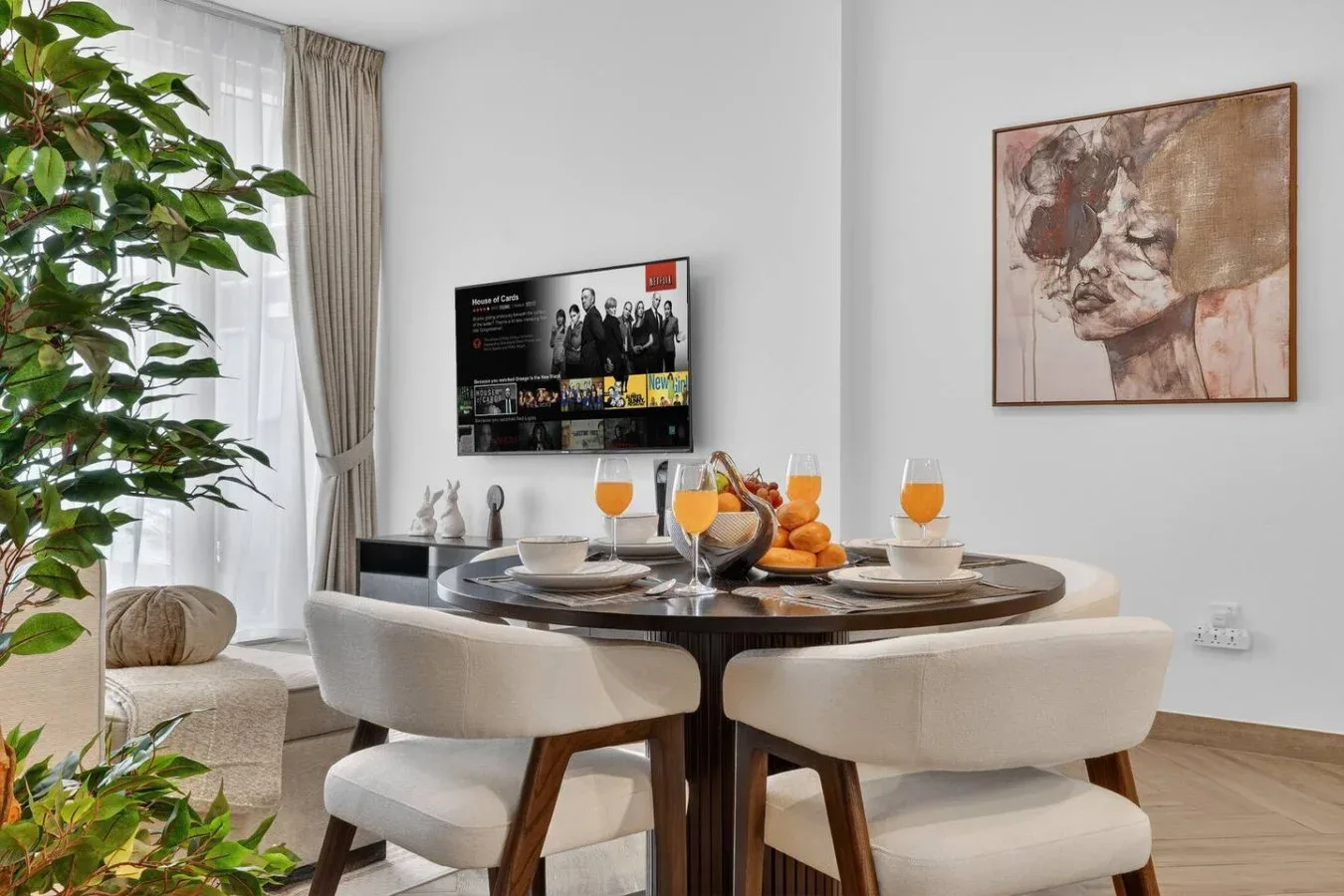 A dining area with a set table beside a window and a potted plant.