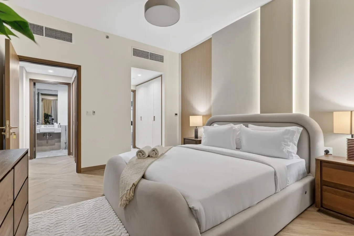 A bright bedroom with a neatly made bed and bedside tables.