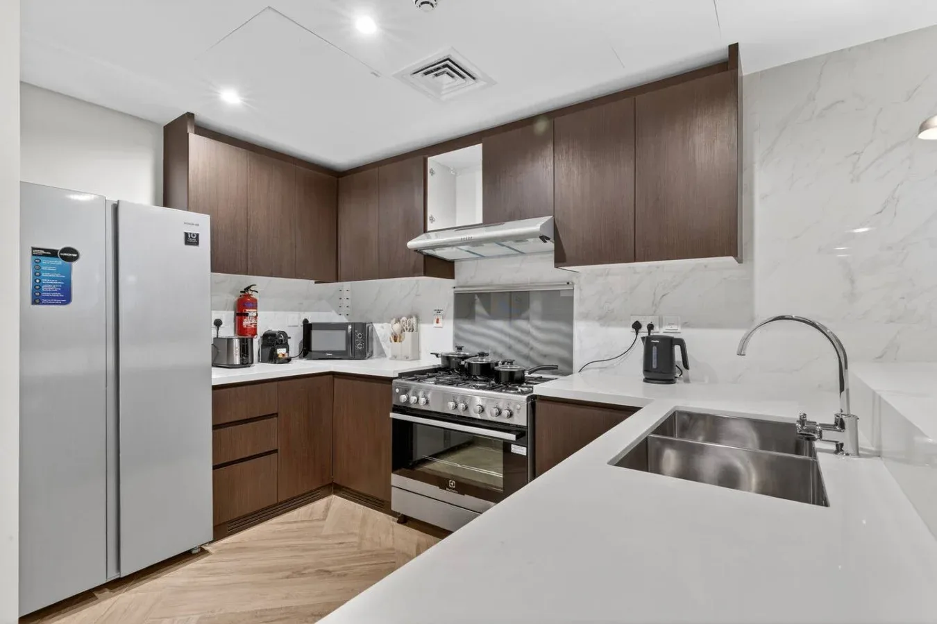 A modern kitchen with dark cabinets, stainless steel appliances, and a large sink.